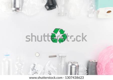Top view of cans, plastic and glass bottles, batteries, paper, recycling sign, carton bottle and pink plastic bag