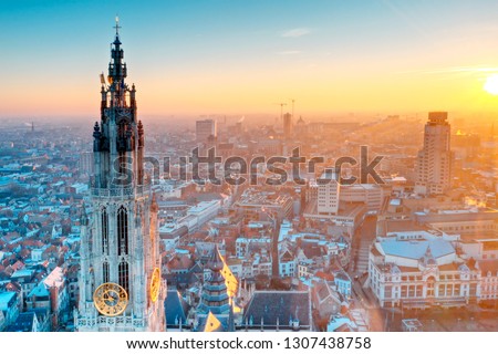 Sunrise at Antwerp where the sky is in orange color. The church tower is standing tall among the buildings in the town. Royalty-Free Stock Photo #1307438758