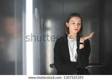 Young female office worker is indifferent. Young woman in the elevator is tired of her job.