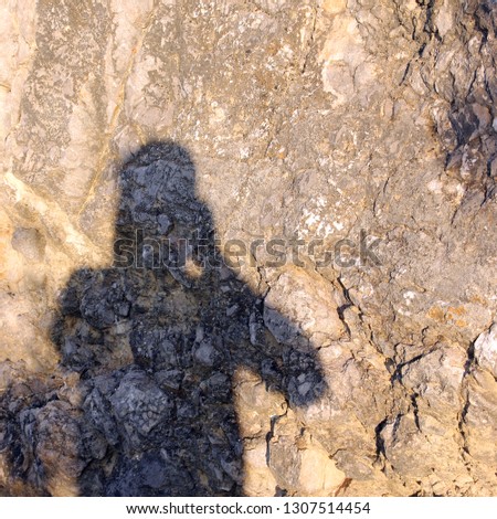the shadow of the photographer on the stone surface background of the cliff in the summer or photographer taking pictures of his shadow