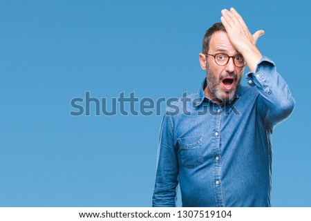 Middle age hoary senior man wearing glasses over isolated background surprised with hand on head for mistake, remember error. Forgot, bad memory concept. Royalty-Free Stock Photo #1307519104