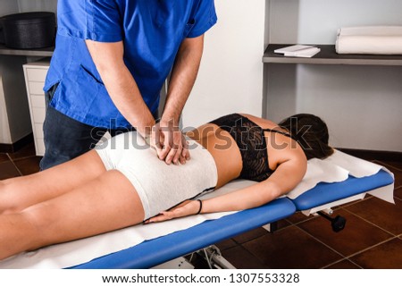 Osteopath working on the back of a girl lying on an examination couch applying pressure to her bones realigning and manipulating them Royalty-Free Stock Photo #1307553328