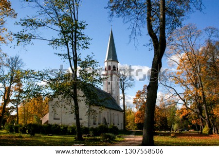 Old white church with light blue coloured dome in the autumn plyos in the light of a sunny day. Non renovated traditional old Europe church in autumn landscape and blue heaven sky background