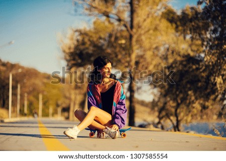 beautiful woman is sitting on the skateboard on the background of the track