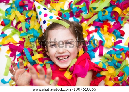 Birthday. A child in a red dress on a background of bright confetti celebrates a bright event. Have fun-image