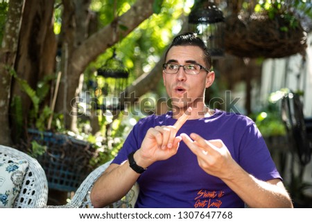 a man wearing purple t-shirt using his  hand gesture to help explain things while he is speaking Royalty-Free Stock Photo #1307647768