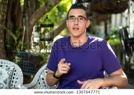 a man wearing purple t-shirt using his  hand gesture to help explain things while he is speaking Royalty-Free Stock Photo #1307647771
