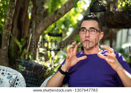 a man wearing purple t-shirt using his  hand gesture to help explain things while he is speaking Royalty-Free Stock Photo #1307647783