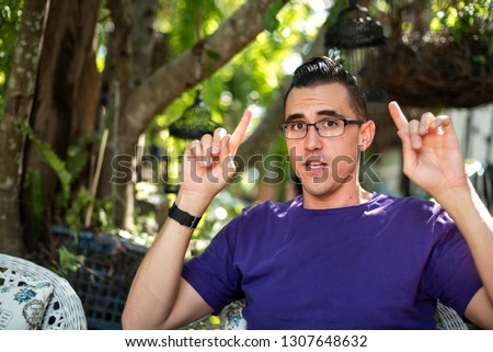 A man wearing purple t-shirt pointing his two fingers upward Royalty-Free Stock Photo #1307648632