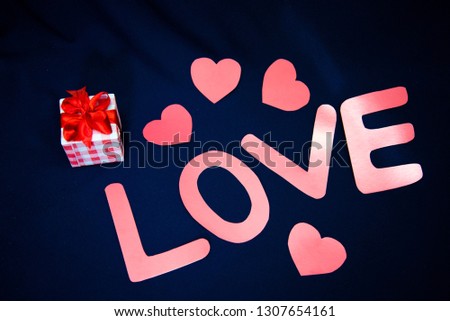 Valentine's Day, the word love in pink letters with hearts and a gift on a dark blue background