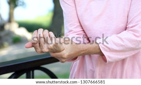 Old woman stretching numb arm, weakness of muscles in senior age, arthritis