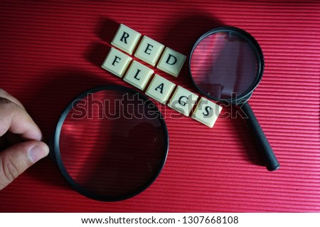 Conceptual photo using magnifying glass and alphabets regarding red flags in auditing program. Selectively focused.