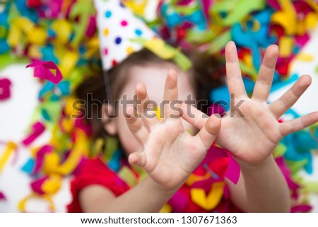 Birthday. A child in a red dress on a background of bright confetti celebrates a bright event. Have fun-image