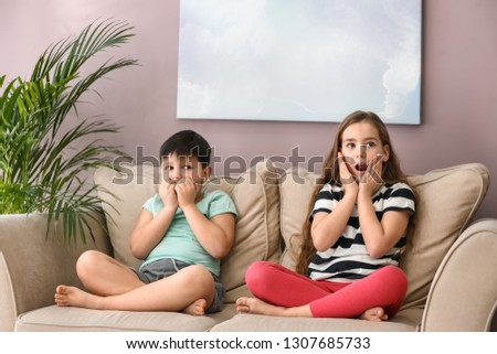 Emotional little children watching cartoons on TV at home
