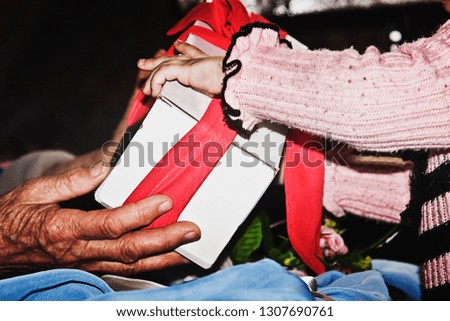A child takes a gift from the hands of an old grandmother