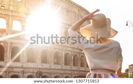 Beautiful young woman in fashion dress alone in front of colosseum in Rome at sunset.