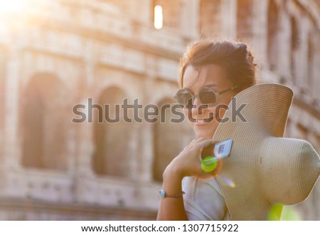 Beautiful young woman in fashion dress alone in front of colosseum in Rome at sunset.