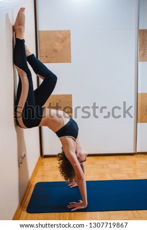 Sporty beautiful young woman practicing yoga, doing Splits Exercise, Monkey God Pose, stretching the thighs, hamstrings, groins, working out wearing black sport