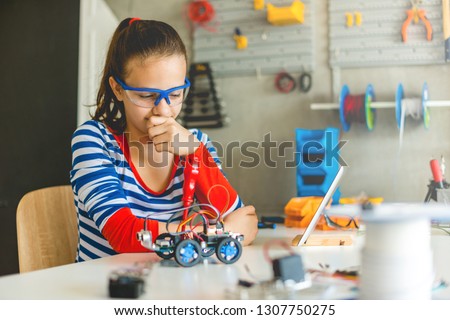 Teenage girl looking at robotic car, school project