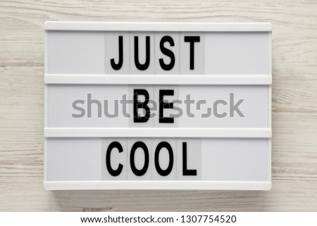 Modern board with text 'Just be cool' on a white wooden background, top view. From above, flat lay, overhead. Close-up.