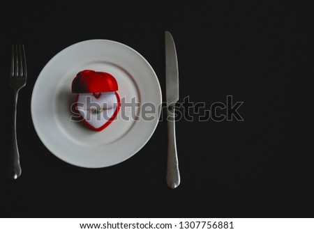 beautiful black background, a red box with a ring on a white dish, a day in the loved ones