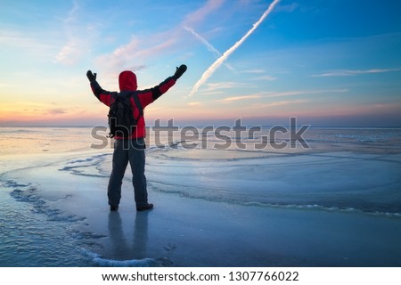 Nature photographer traveler on the frozen lake during sunrise in winter. Beautiful colorful landscape with people
