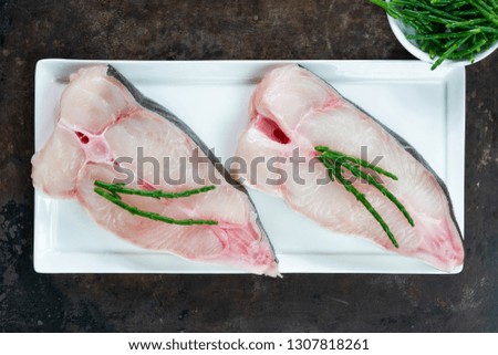 Two raw halibut steaks garnished with samphire - top view