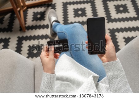 High angle above top view and cropped photo of lady in denim jeans clothes sitting inside loft interior space in restaurant. She holding portable telephone equipment and plastic card in hands