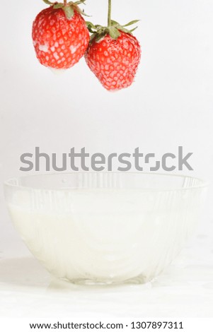 Splashes of milk from falling strawberries, white background.