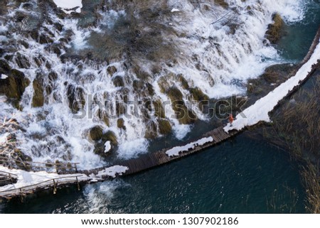 Tourist navigating the snow covered wooden pathways of the Plitvice Jezero National Park in winter