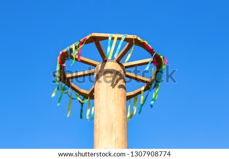 Shrovetide celebration in Russia. Wooden wheel with colorful ribbons on blue sky background