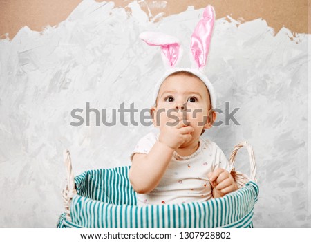 Portrait of a cute baby dressed in Easter bunny ears in a basket holds egg happy easter concept