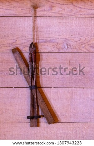 Decorative wooden skies hanging on a rope tied to a nail in a wooden wall