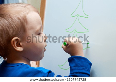 The little boy learns to draw on a white board.