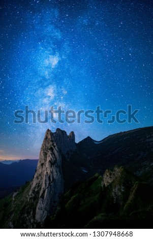 Mountain landscape in the Swiss Alps with jagged peaks and a pristine blue mountain lake in the valley far below. Amazing milky way picture in the swiss alps.