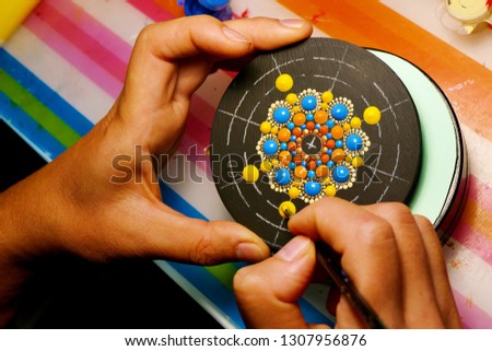 Drawing with a brush a mandala on round wood disk, closeup Royalty-Free Stock Photo #1307956876