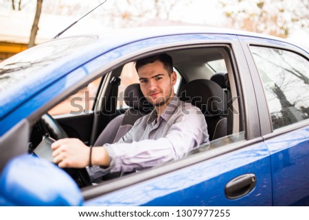 Smiling man wearing glasses sitting behind the wheel of his car driving through the city