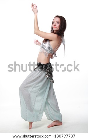 Delightful young woman with long dark hair dancing belly dance
