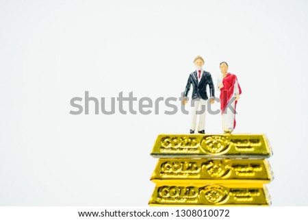 Miniature people :Senior Indian couple and rich people stand on pile of gold bar on white background.Concept for Money, Financial, Business planning,Gold business and Rich people in India.