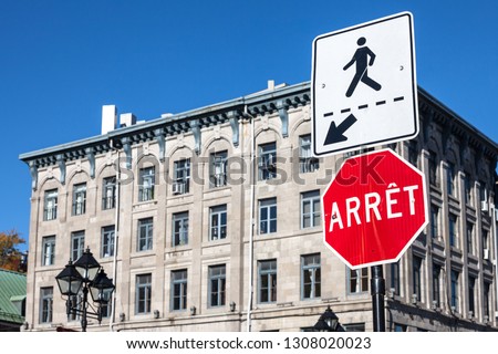 Quebec Stop Sign, obeying by bilingual rules imposing use of French language on roadsigns, translating Stop into Arret, taken in Montreal, Canada, next to a sign indicating a pedestrian crossing

