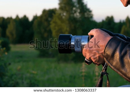 outstretched hands of a man, a photographer, in a leather jacket, photographing objects near the forest in nature