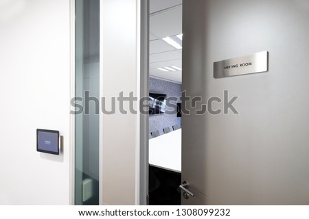 Door with knob opening to the meeting room, with status monitoring and controlling electronic device in front of the room