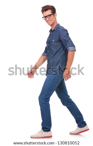 casual young man walking away from the camera while looking at it. isolated on a white background