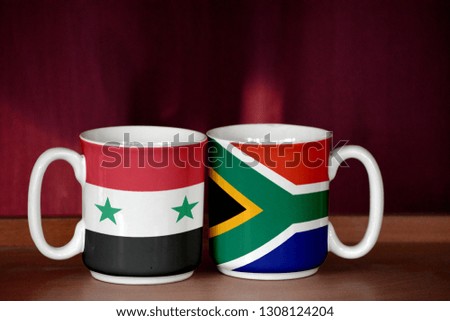 South Africa and Syria flag on two cups with blurry background