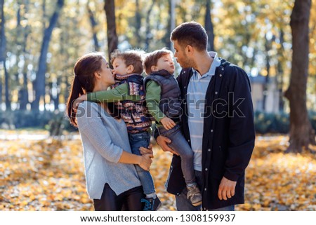 Natural pictures of a happy family of four having fun outsiade on a sunny autumn day. Togetherness and happiness concept
