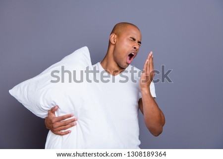 Close up photo unhealthy dark skin he him his macho bald head tired yawn yell scream shout hold pillow sleep and walk sleepless night wearing white t-shirt outfit clothes isolated grey background