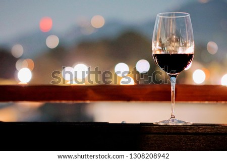 A glass of wine in a restaurant  dinning room or rooftop bar, with bokeh background of the city light, good view and romantic scene, for valentine dating or celebrate special day, with copy space,