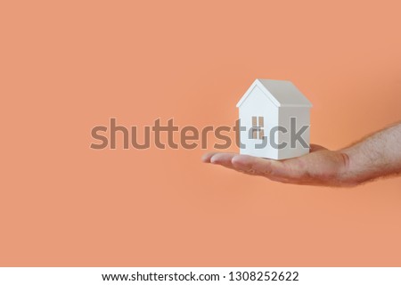 Male hand with model house. Copy space. Living coral Royalty-Free Stock Photo #1308252622