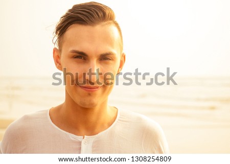 man in white shirt and pants acts yoga warrior pose on the beach in the morning silhouetted against sunlight.businessman balance