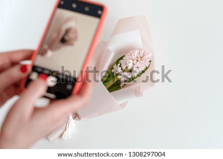 Female hands taking photo of beautiful flowers with smartphone. Instagram photographer blogging workshop concept